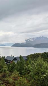 ein Haus auf einem Hügel neben einem Gewässer in der Unterkunft Tranquilo Austral in Puerto Tranquilo