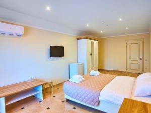 a bedroom with a bed and a desk and a television at Guest house Nikolaevsky in Bilhorod-Dnistrovskyi