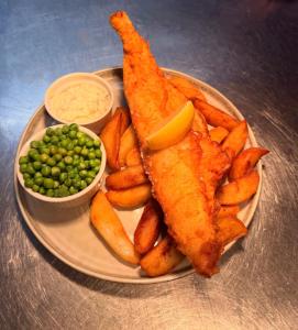 a plate of fish and chips with peas and a side of peasuggest at The Old Manor House Hotel in Keynsham