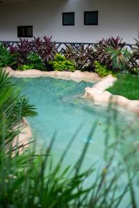 a large pool of water in a yard with plants at Spacious Loft with Balcony Near Hotel Zone Palais Tulum by Waves in Tulum