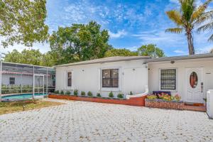 a white house with a palm tree and a swimming pool at 4 Mi to Surfside Beach! North Miami Apt in North Miami