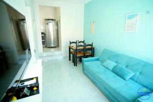 a living room with a blue couch and a table at Praia Studios in Vila Velha