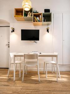 a white dining room table with white chairs and a tv at Sanremo Apartments - Marilux in Sanremo