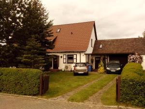 a white house with two cars parked in the driveway at Ferienwohnung Hiddenseeblick 1 in Dranske +3 photos