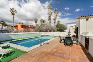 a patio with a table and chairs next to a swimming pool at Exclusively located Golf Villa with heated pool in San Miguel de Abona