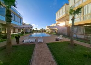 a swimming pool with chairs and umbrellas next to a building at Diamond Blue in Sidi Rahal