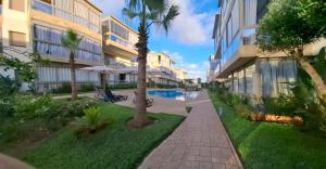 a resort courtyard with a swimming pool and palm trees at Diamond Blue in Sidi Rahal