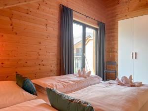 two beds in a room with wooden walls and a window at Rattendorf 13A in Rattendorf