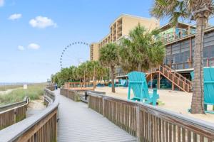 a boardwalk to the beach with a beach chair and a roller coaster at Penthouse Oceanfront Studio VR + Mural + Minibar in Myrtle Beach