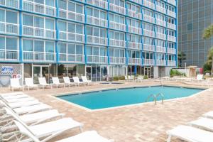 a pool in front of a building with lounge chairs at Penthouse Oceanfront Studio VR + Mural + Minibar in Myrtle Beach