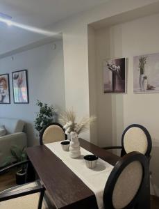 a dining room table with chairs and a vase with flowers at Apartman Una in Leskovac