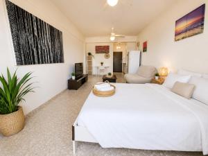 a bedroom with a large white bed and a living room at The Seafront Pearl in Larnaca