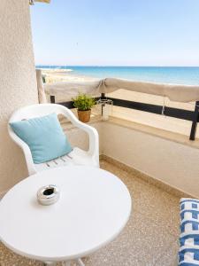 a white chair and a table with a view of the beach at The Seafront Pearl in Larnaca
