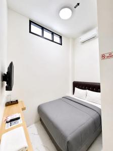 a bedroom with a bed and a desk and two windows at Sekuto Inn by Sawala in Tegal