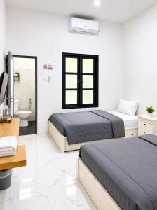 a bedroom with two beds and a sink and a mirror at Sekuto Inn by Sawala in Tegal