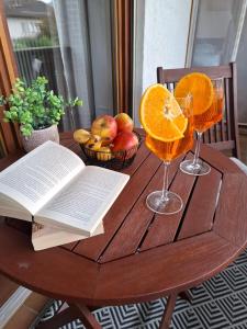 a table with two glasses of orange juice and an open book at Ferienwohnung See und Sonne in Obing