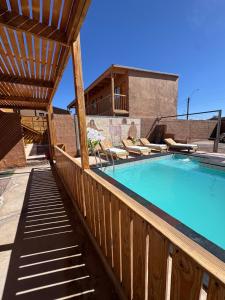 a swimming pool on a deck with a wooden fence at Hostal Pablito in San Pedro de Atacama