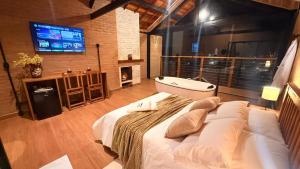 a bedroom with a large bed and a television at Chalés Raios de Sol in Monte Verde