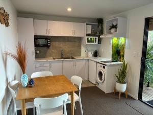 a kitchen with white cabinets and a table and chairs at Rusty Fish in Paihia +4 photos