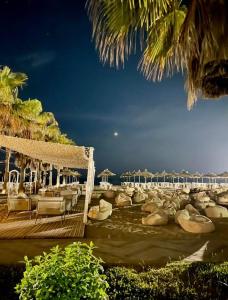 a beach with chairs and umbrellas and the ocean at Hamallaj Bliss in Draç +6 photos