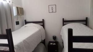 a bedroom with two beds with white comforters at Suites e Cia - Pousada in Volta Redonda
