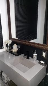 a bathroom sink with a large mirror above it at Suites e Cia - Pousada in Volta Redonda