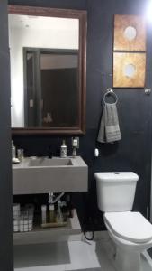 a bathroom with a sink and a toilet and a mirror at Suites e Cia - Pousada in Volta Redonda