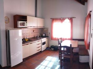 a kitchen with a white refrigerator and a table at COMPLEJO LLATANI in Los Reartes