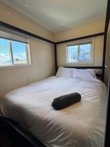 a large white bed with a black pillow on it at Bright & Spacious Full Family Home in Vancouver