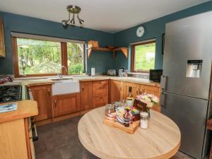 a kitchen with a wooden table and a stainless steel refrigerator at Puidrac Cottage in Lochearnhead +13 photos