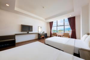 a hotel room with two beds and a flat screen tv at Dolphin Bay Hotel Nha Trang in Nha Trang