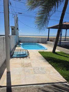 a swimming pool with two chairs and a palm tree at PÉ NA AREIA EM Pirangi do Norte in Parnamirim