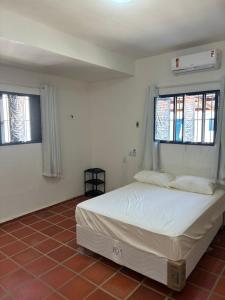 a bedroom with a white bed and two windows at PÉ NA AREIA EM Pirangi do Norte in Parnamirim