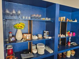 a blue shelf with plates and glasses and a vase with flowers at PÉ NA AREIA EM Pirangi do Norte in Parnamirim