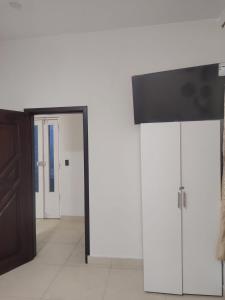 a room with white walls and a door with a television at Minidepartamento Independiente in San José de Chaltura