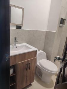 a bathroom with a toilet and a sink and a mirror at Minidepartamento Independiente in San José de Chaltura