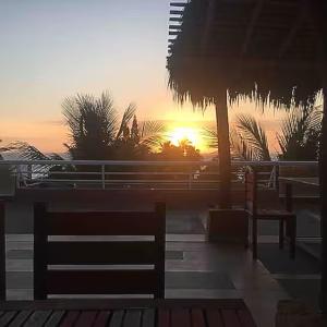 a sunset with a bench and a table and palm trees at Macedonia in San Clemente