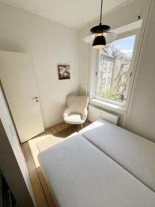 a bedroom with a bed and a chair and a window at Beautiful 2 Bedroom Apartment on Borgergade in Aalborg