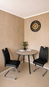 a table and two chairs and a clock on a wall at Košice Kysucka Apartment in Košice