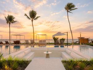 a swimming pool with palm trees and the ocean at Resort beira mar in Porto De Galinhas