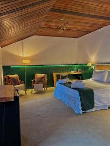 a bedroom with a bed and chairs in a room at Casa Capivari Boutique in Campos do Jordão