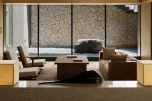 a lobby with chairs and a table and a stone wall at Banyan Tree Higashiyama Kyoto in Kyoto