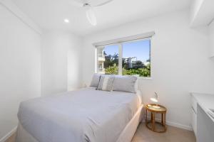 a white bedroom with a bed and a window at 6 Baywatch Apartments in Coolum Beach +11 photos