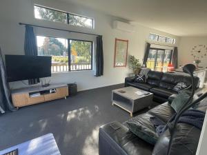 a living room with a couch and a flat screen tv at Playground Fun on Town Doorstep! in Ohakune