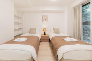 two beds in a room with a window at 直达池袋丨东京丨银座无需换乘丨地铁站步行3分钟 丨商店街旁 生活出行方便 in Tokyo