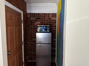 a refrigerator in a room with a brick wall at Madeira Suite in Fort Worth