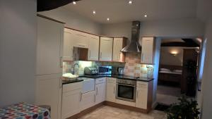 a kitchen with white cabinets and a stove top oven at The Gate House Barn in Stanton in Peak