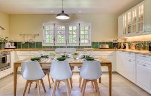 a kitchen with a wooden table and white chairs at Maisons Falourdel in Soulles