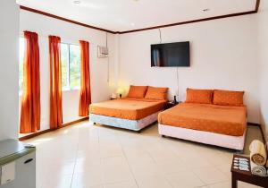 a bedroom with two beds and a tv on the wall at Kyleville Resort by Hiverooms in Dalaguete +14 photos