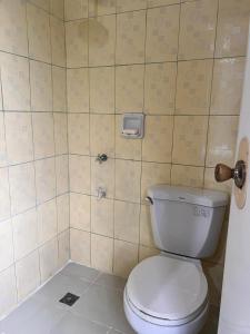 a bathroom with a toilet and a tiled wall at Kyleville Resort by Hiverooms in Dalaguete